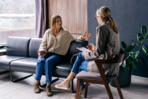 An excited patient sitting on the couch in the office talks about the problems to the psychologist.