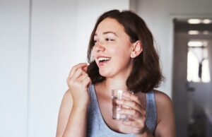 Do what it takes to maintain good health. cropped shot of a young woman taking medication at home.