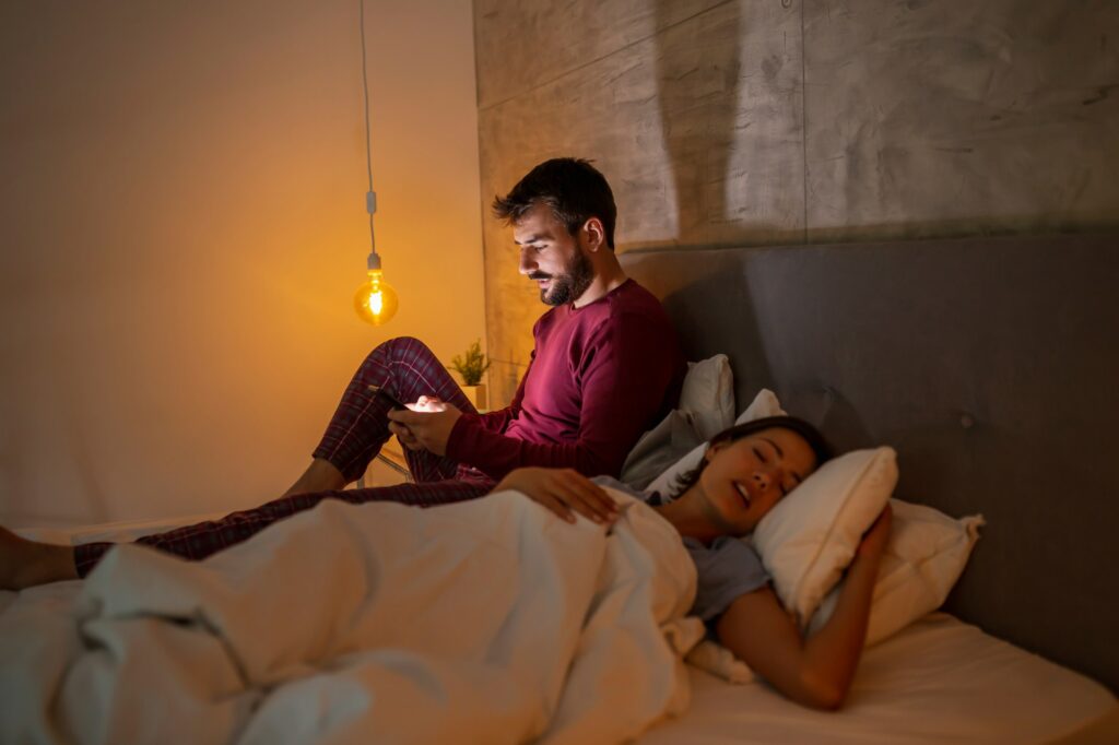 Man having sleeping disorder using smart phone in bed