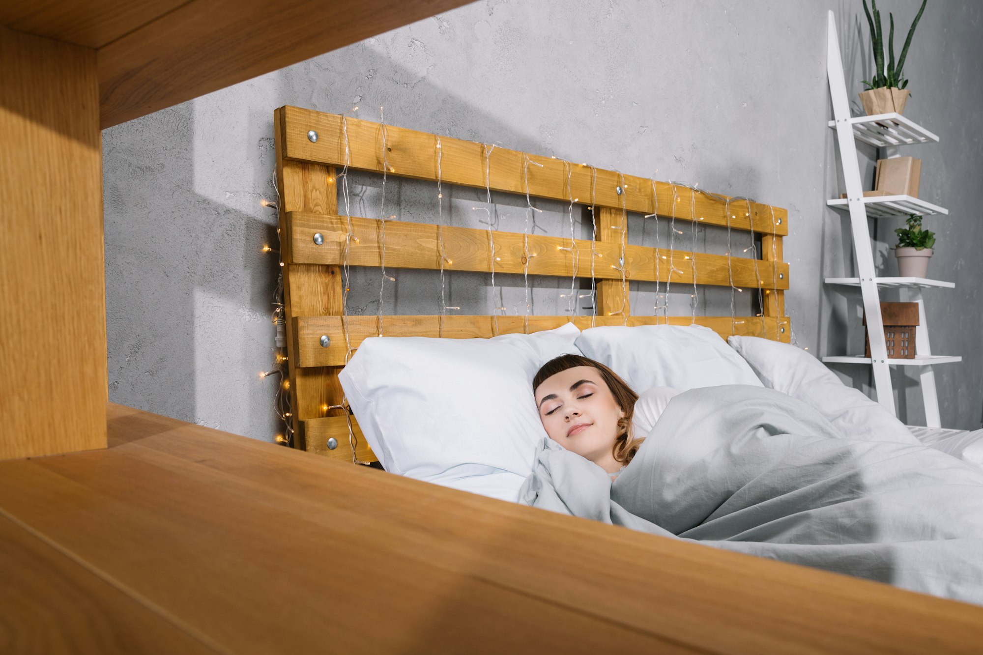 view through shelves on girl sleeping on white pillows in bedroom