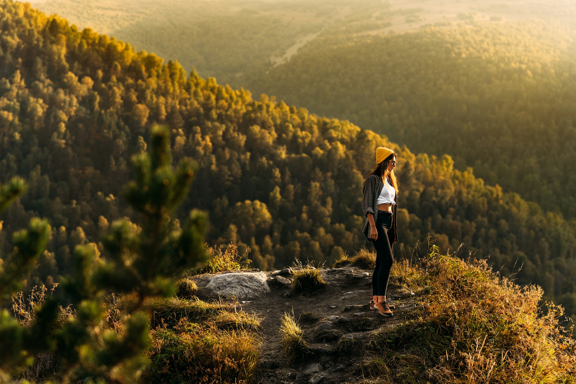 A woman meets the sunset in the mountains. Man travels in the mountains. Mountain tourism