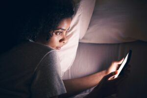 Insomnia, night and phone with woman in bedroom for social media app, streaming and networking. Com